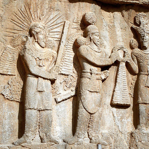 Mithra on the left: Investiture of Sassanid emperor Ardashir I or II (3rd century CE bas-relief at Taq-e Bostan, Iran. On the left stands the yazata Mithra with raised barsom, sanctifying the investiture.