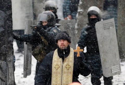 Ukrainian Greek Catholic Church priest prays as he stands before pro-European Union activists during clashes in central Kiev, Ukraine